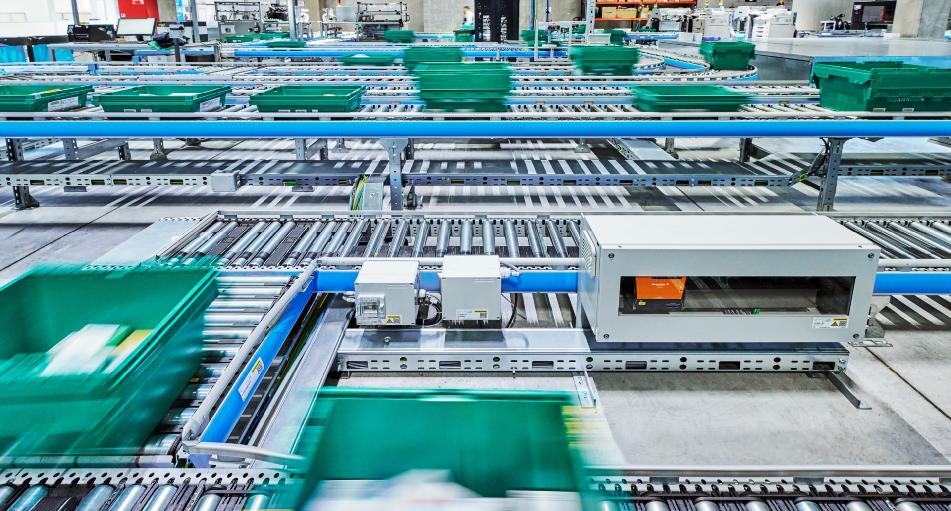 Green distribution totes moving through a network of conveyors