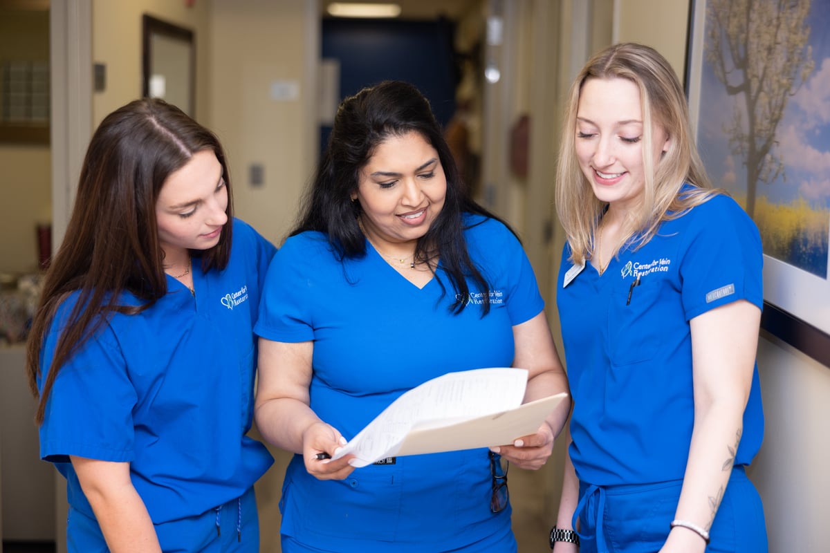 Three Center for Vein Restoration clinical team members reviewing a patient chart in a clinic hallway
