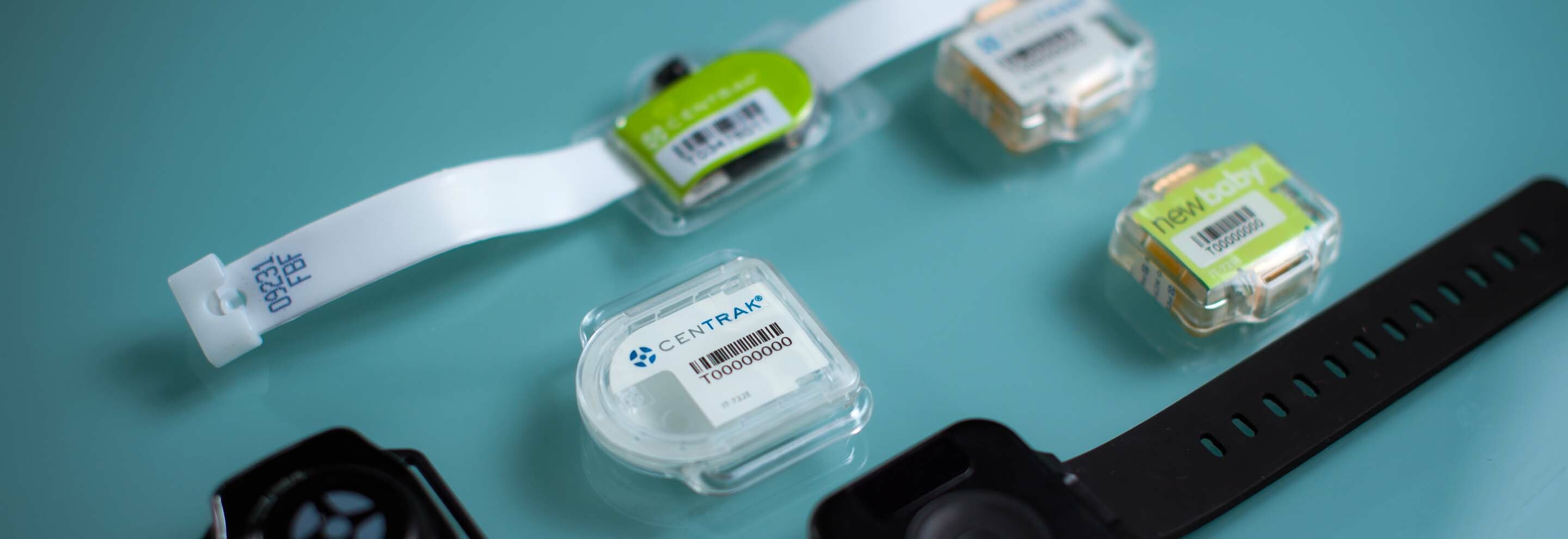 CenTrak location tags and wearable bands arranged on a blue surface