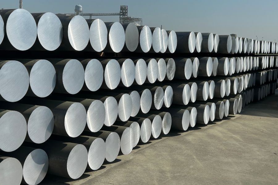 Rows of cylindrical aluminum billets stacked outdoors