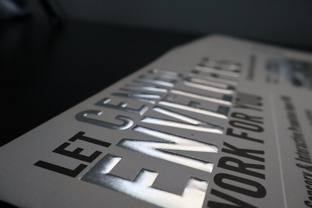 Raised silver foil lettering on a textured white Cenveo envelope
