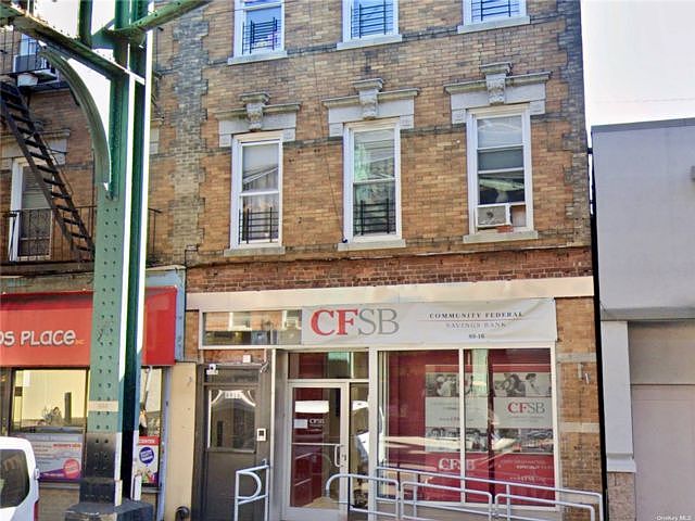 Archival photograph of the CFSB branch on Jamaica Avenue, with a green elevated railway support beside the storefront