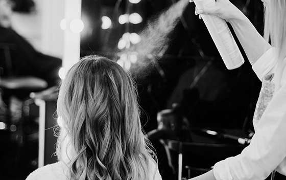 A stylist sprays a client's hair in a salon
