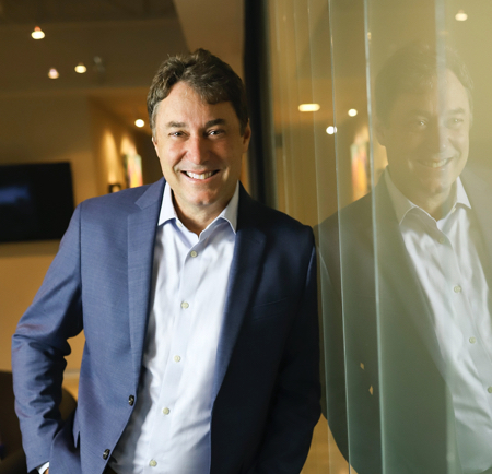 Chadd Mason standing beside a glass wall in Cabana’s Fayetteville office