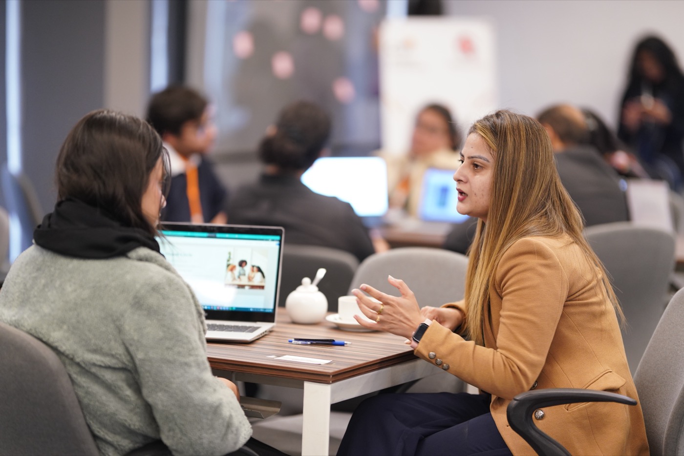 Two women discussing a project across a laptop at the Bank the Unbanked ideathon