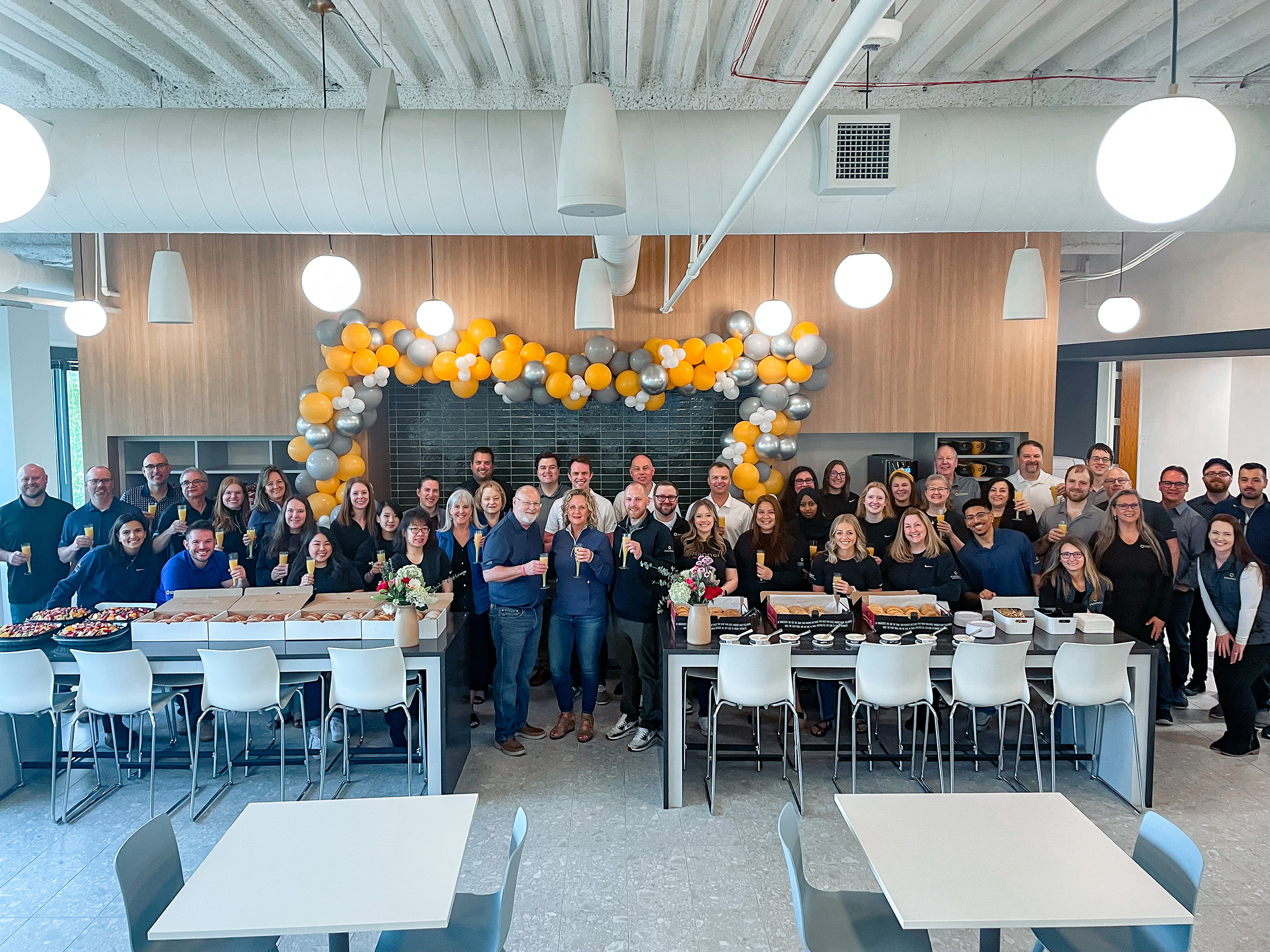 Channel team gathered in its office beneath a garland of yellow and silver balloons
