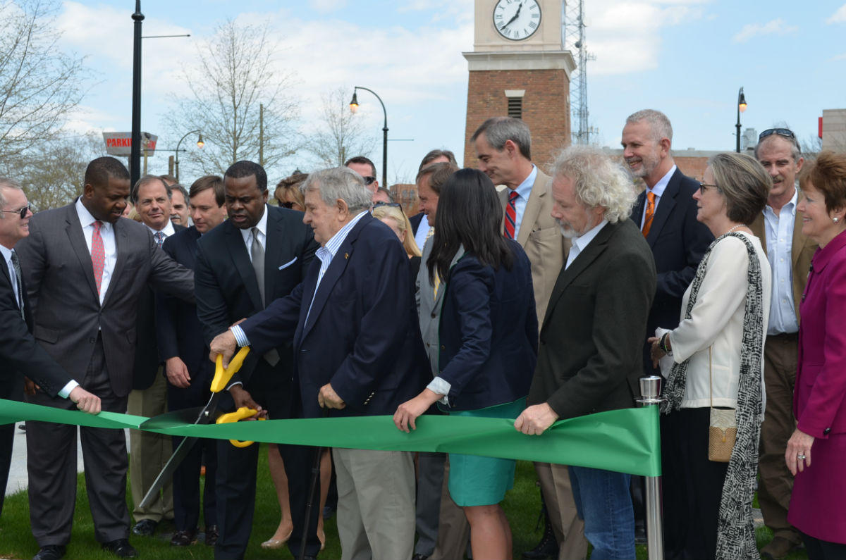 Charlie Loudermilk holding oversized yellow scissors beside Mayor Kasim Reed and other participants at the 2015 park ribbon cutting