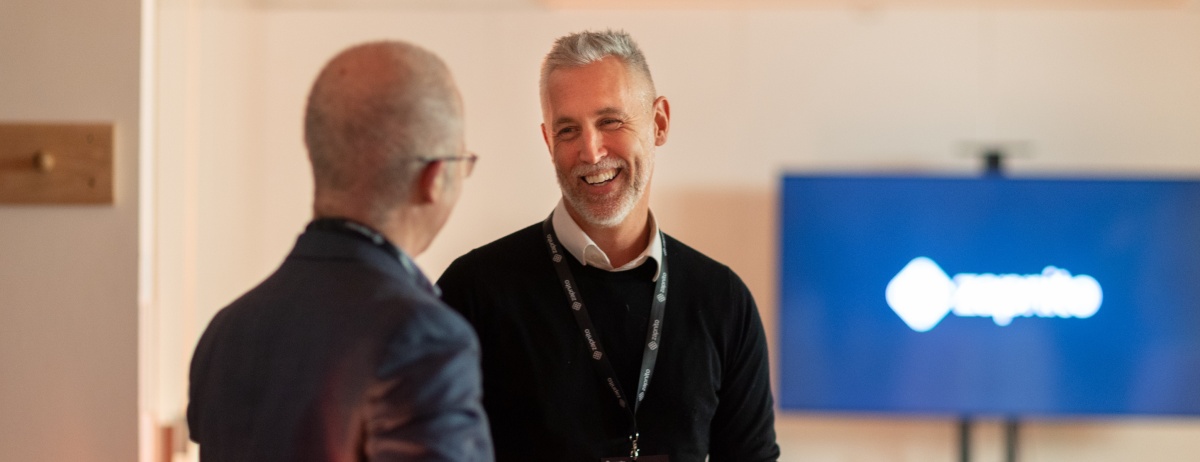 Charles Thiede smiling in conversation with an attendee at a Zapnito customer event