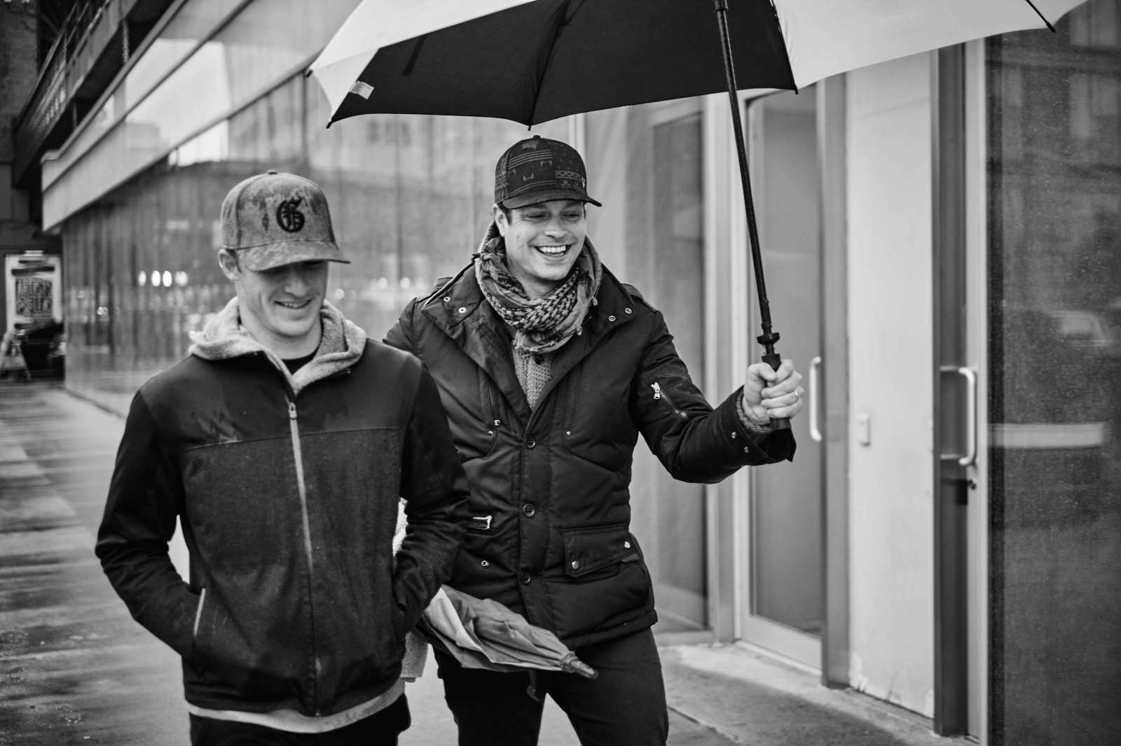 Morgan Hoffmann and Charlie Schaefer walking beneath umbrellas on a rainy city street