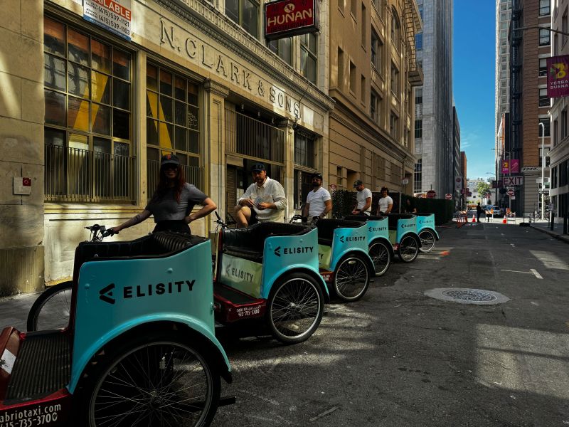 A line of turquoise Elisity-branded pedicabs on a San Francisco street during RSA Conference 2026