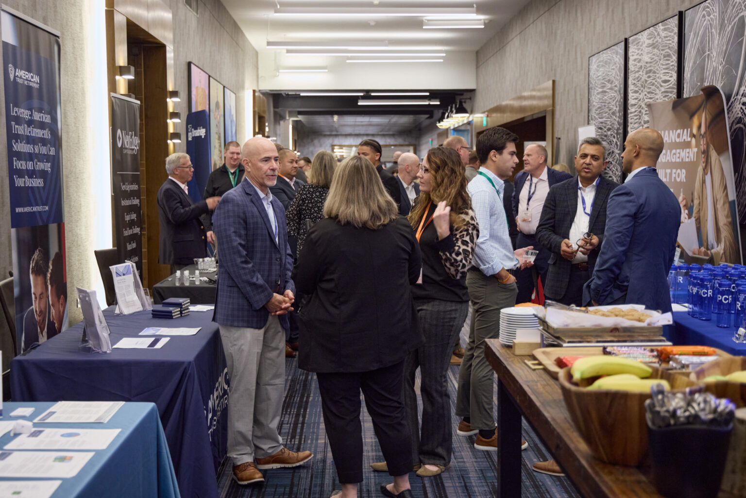 Conference attendees talk beside partner booths at The Hunt in 2024