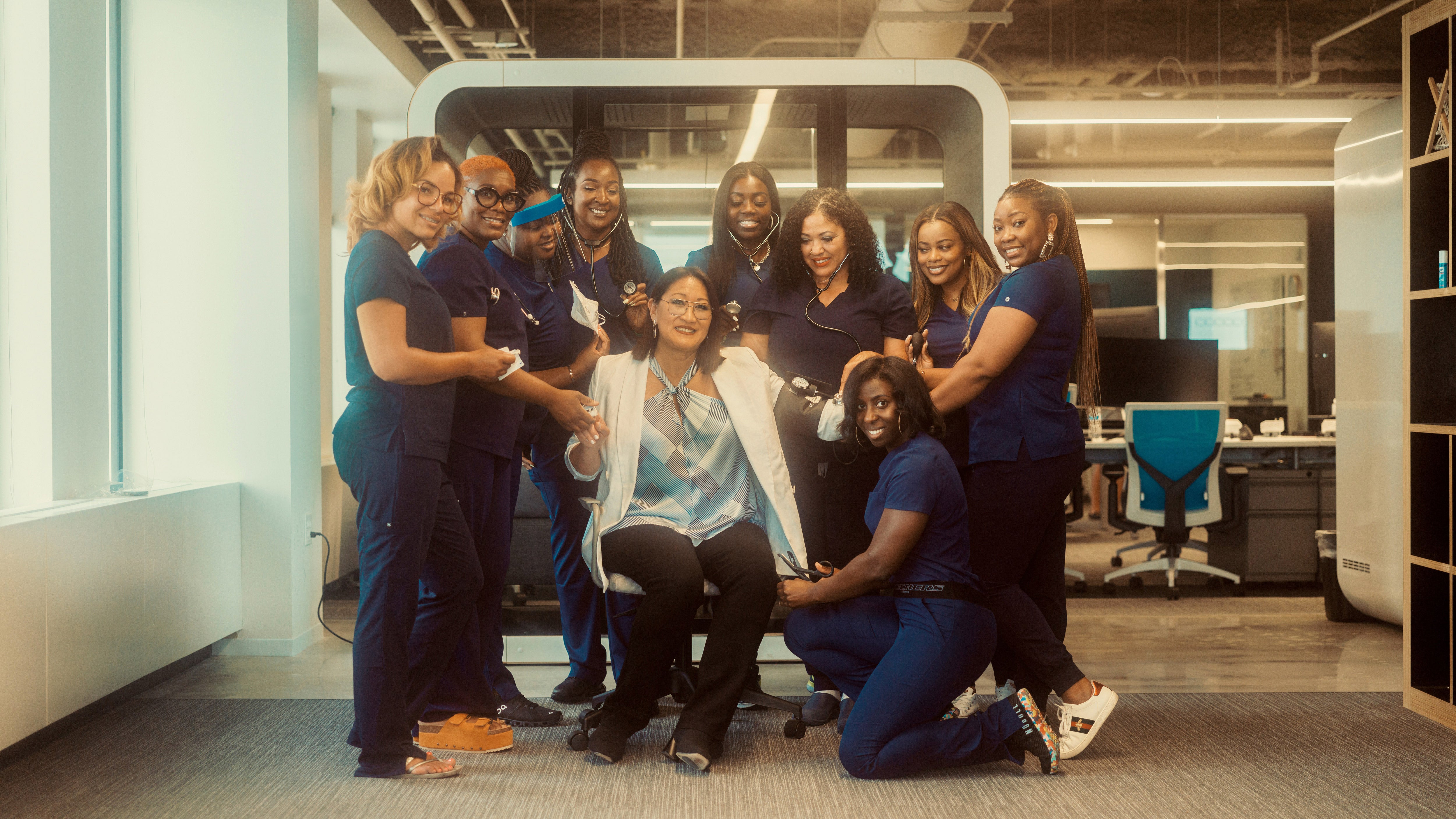 Cherie Kloss seated at the center of a group of SnapNurse professionals in an office