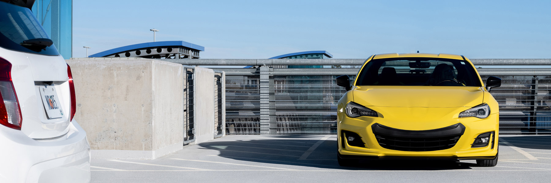 A yellow sports car with a smiling grille in a Charlotte airport parking deck