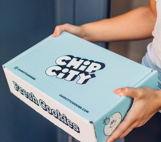 A person holding a branded Chip City cookie shipping box