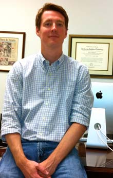 An archival office photograph of Chip Ramsey sitting beside a desktop computer