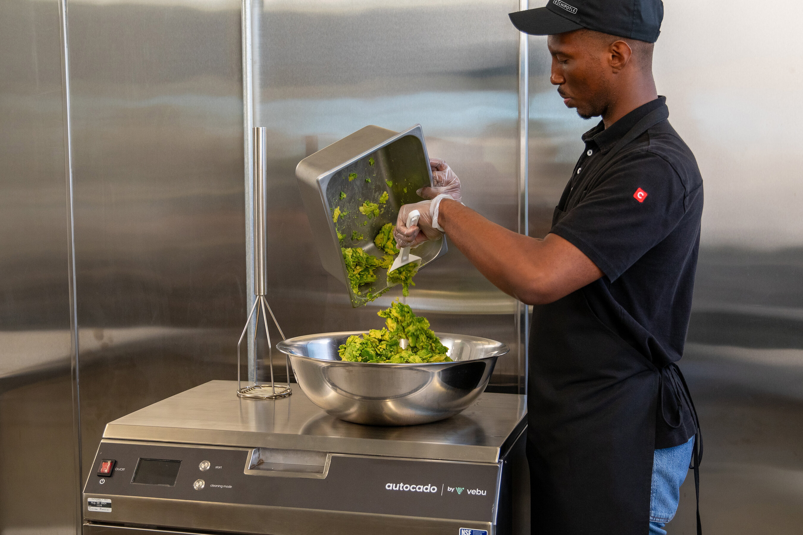 A Chipotle employee empties prepared avocado from Autocado into a steel bowl during its restaurant trial