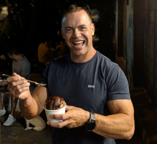 Chris Ashenden smiling with a cup of ice cream and a spoon