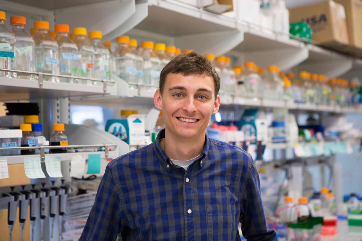 Chris Bahl in a laboratory, standing in front of shelves of bottles and research equipment
