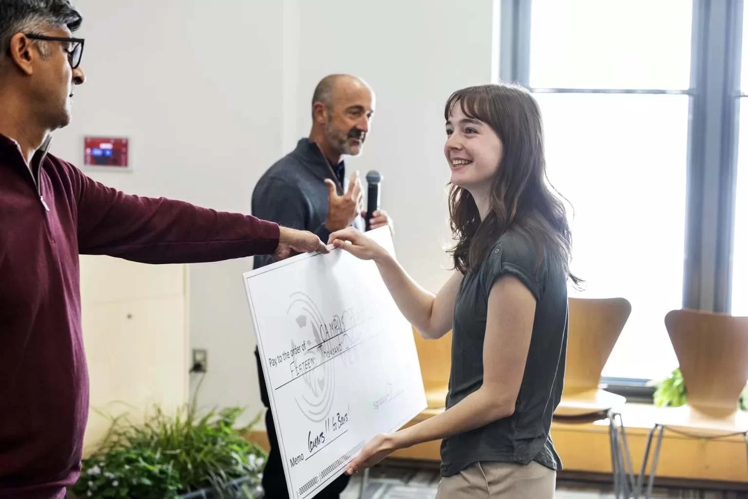Chris Barbin, holding a microphone, with Pranav Ghai and student entrepreneur Ella Beiser at Bates College’s 2025 Bobcat Ventures competition