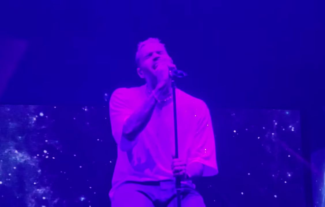 Chris Brown singing onstage under purple light in London in 2023