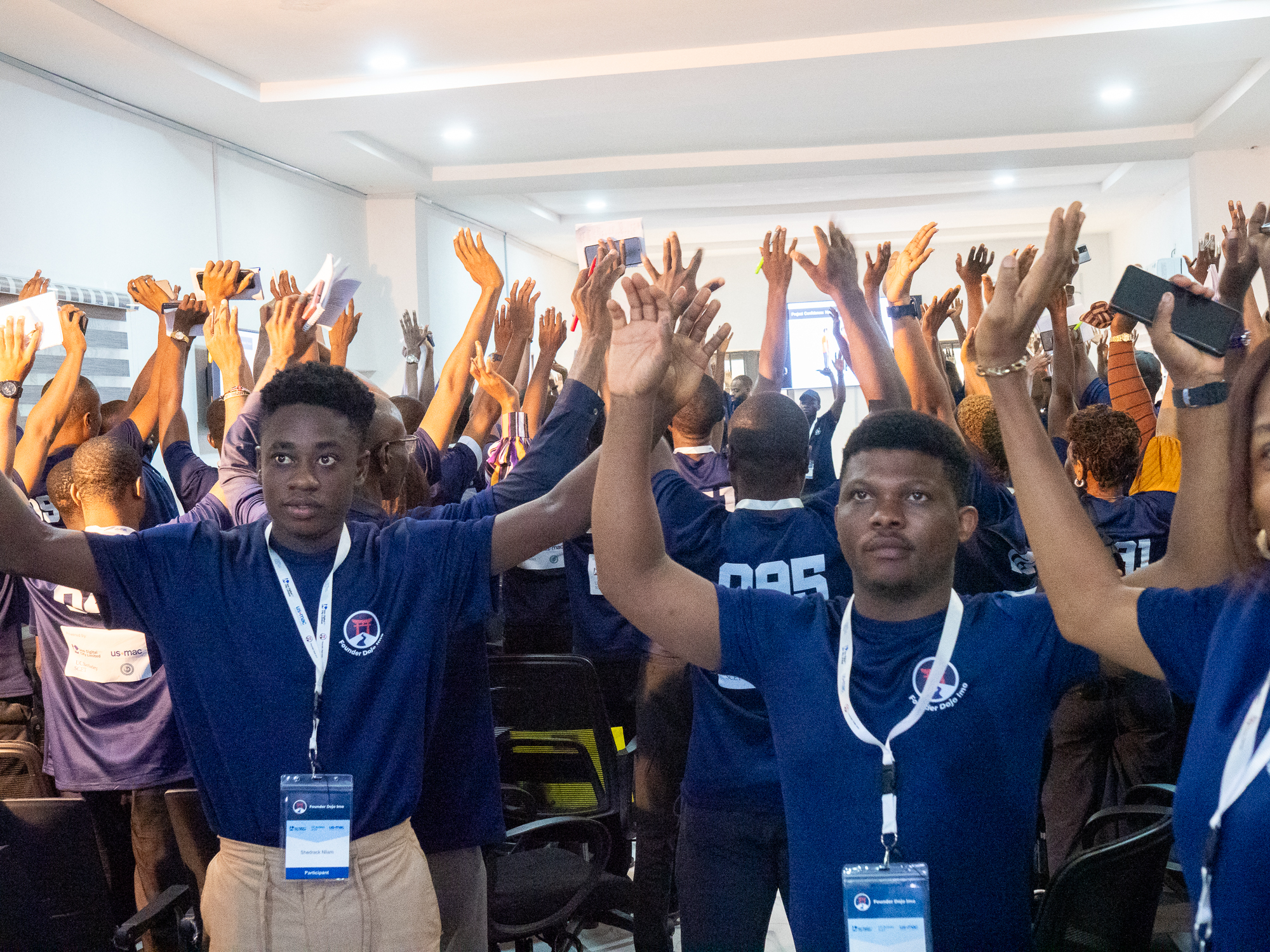 Participants at Founder Dojo Imo raising their hands during a group session