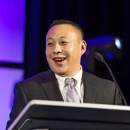 Chris Chuang smiling while speaking behind a lectern