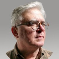 Archival press photograph of Chris Doner wearing glasses, looking to one side