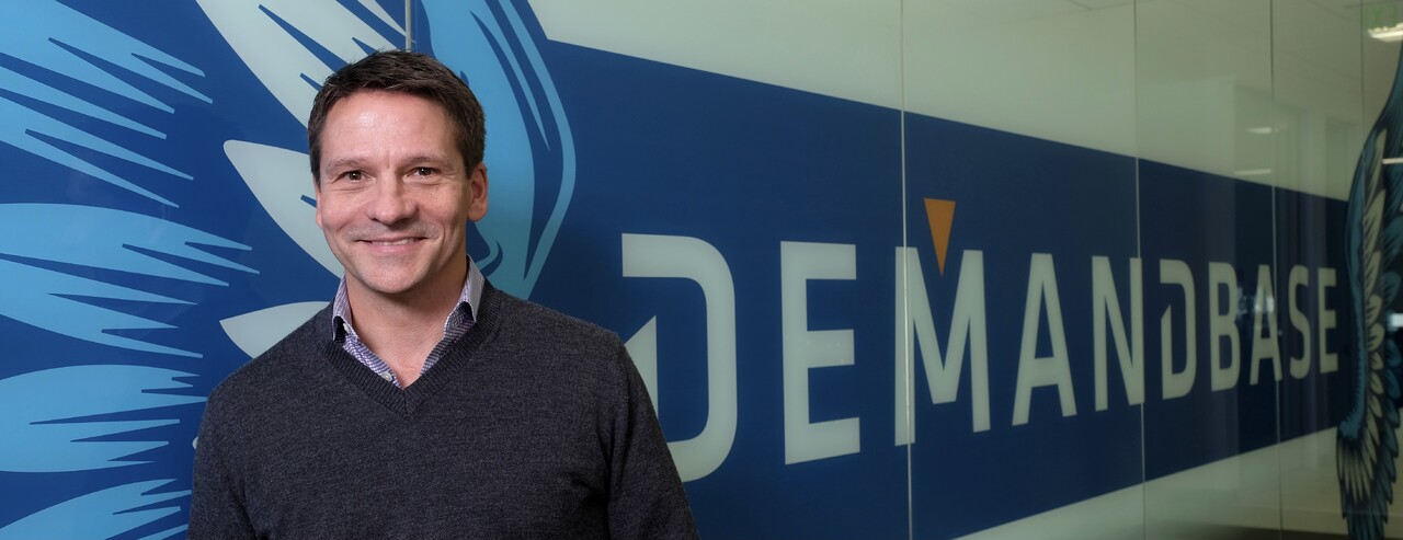 Chris Golec standing beside the Demandbase wall at company headquarters