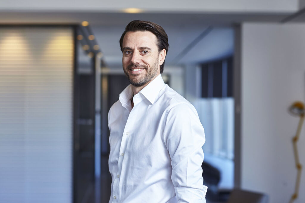 Chris Green standing in an office corridor, wearing a white shirt