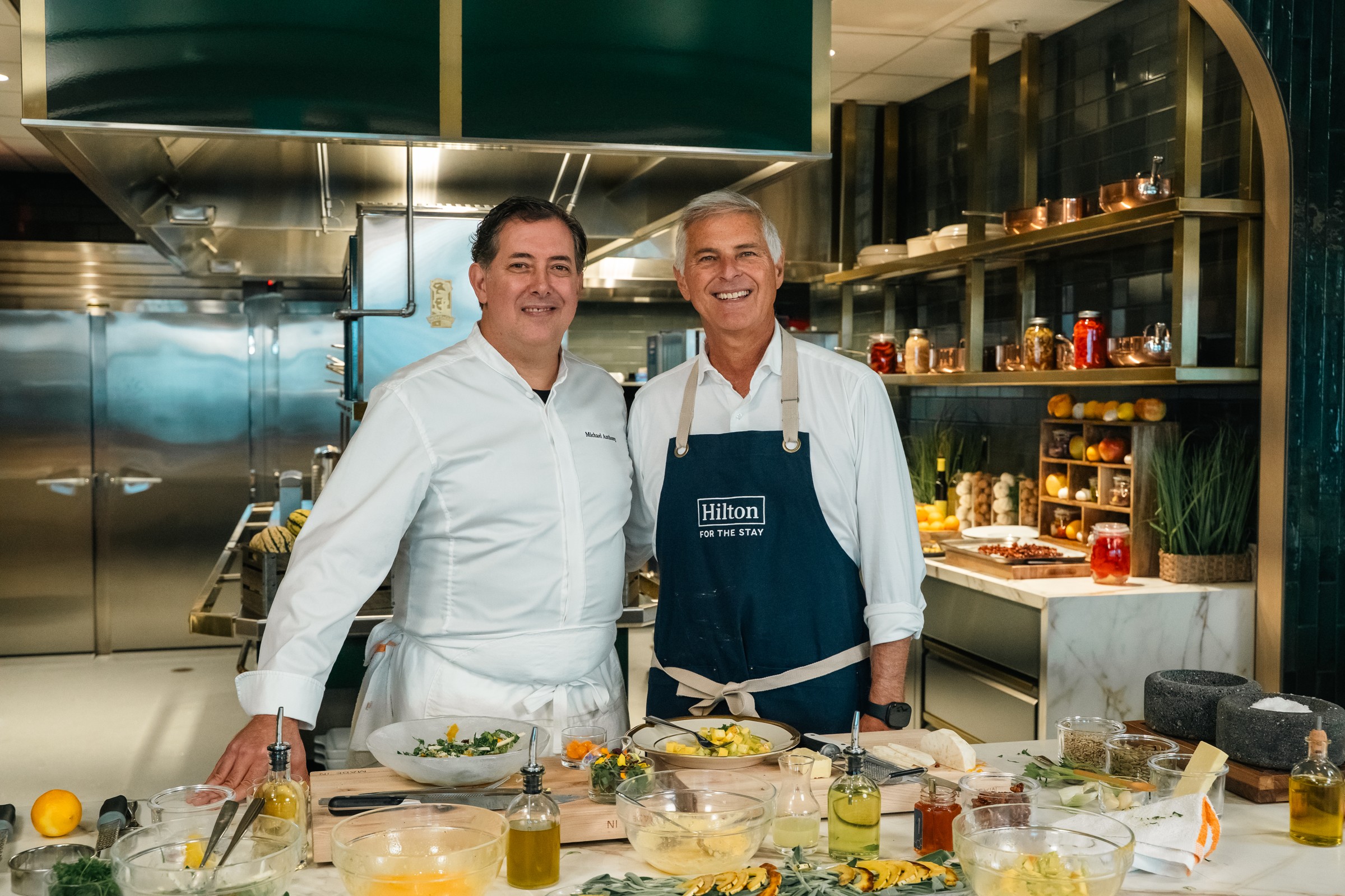 Chef Michael Anthony and Chris Nassetta preparing food in Hilton’s test kitchen