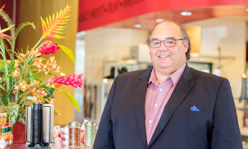 Chris Newcomb standing inside a Newk’s Eatery beside the condiment and tea station
