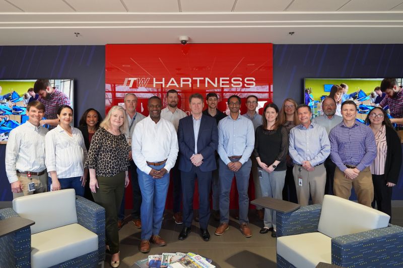 Chris O’Herlihy, standing in the center in a navy suit, with colleagues at ITW Hartness