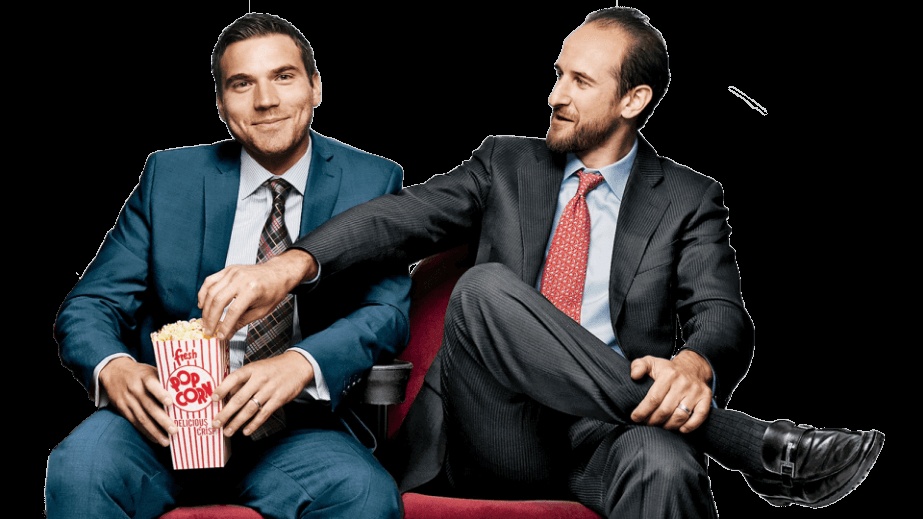 Chris O’Brien, left, and Brett Goldberg seated together, with Goldberg reaching into a popcorn carton