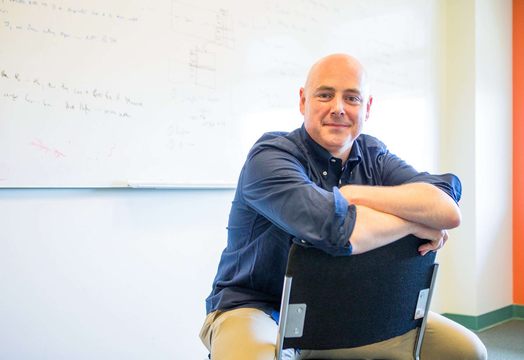 Chris Ré seated in front of a whiteboard