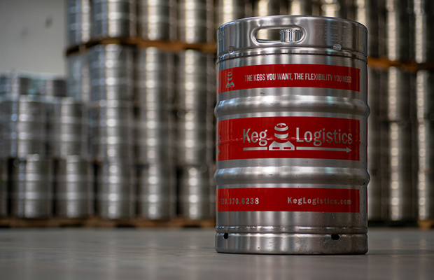A red-branded Keg Logistics stainless-steel keg in front of stacked kegs