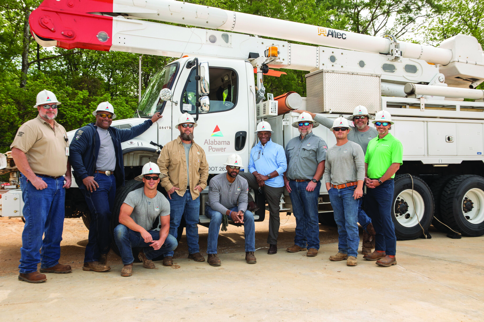 Chris Womack in a light blue shirt with Alabama Power employees beside a utility truck