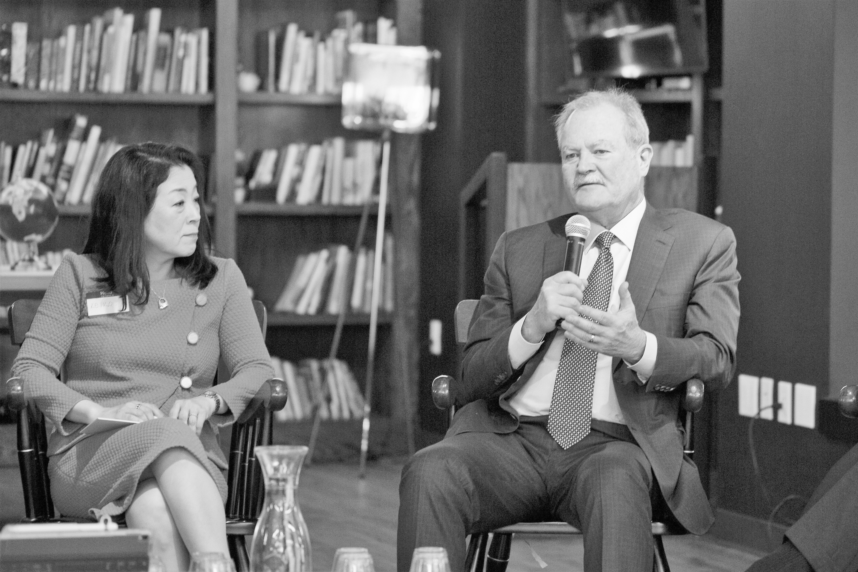 Christa Gyori seated beside a fellow speaker during a conversation in front of bookshelves.