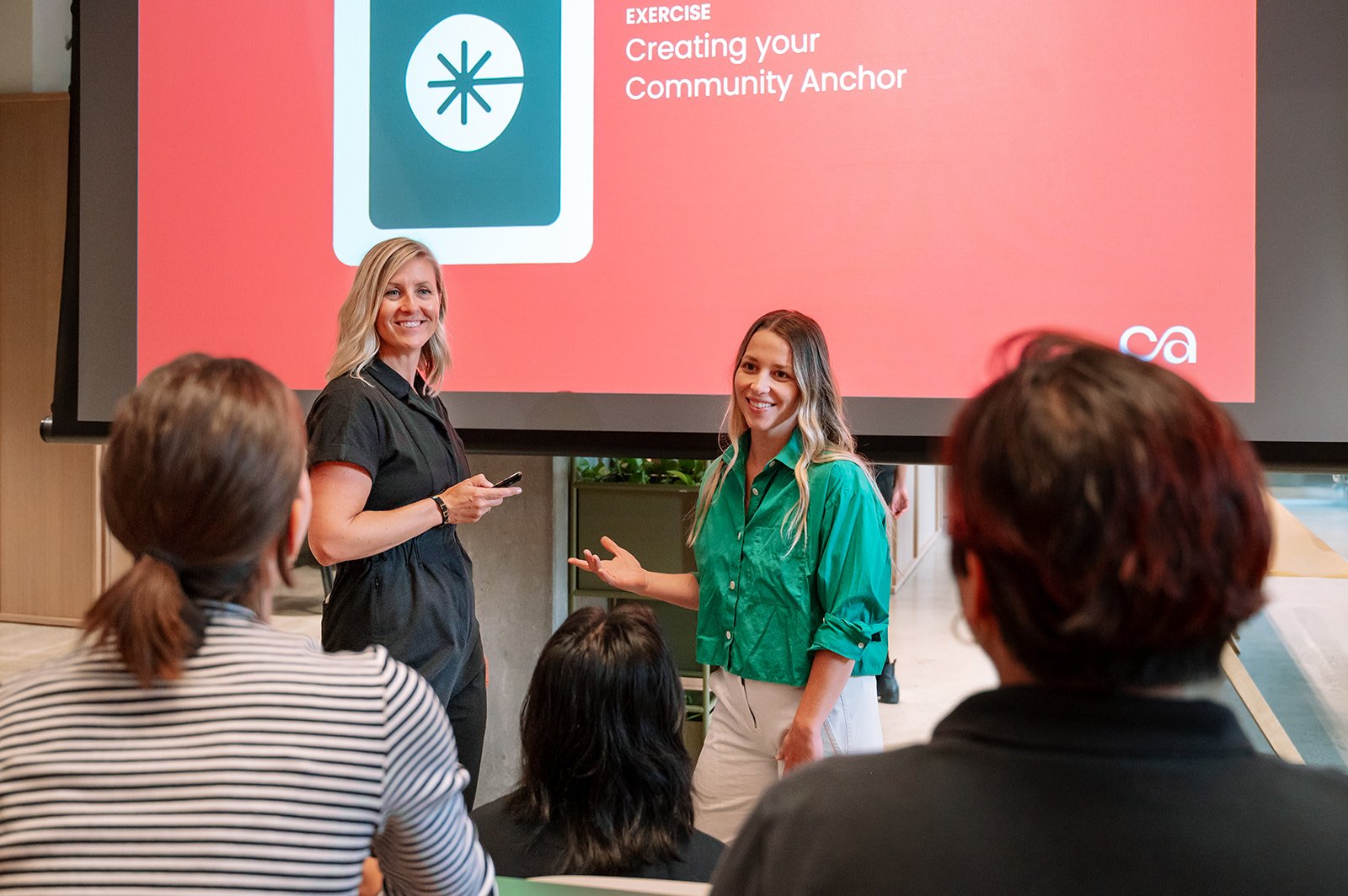 Christa Hull and Michelle Lazar leading a Community Academy exercise in front of an audience