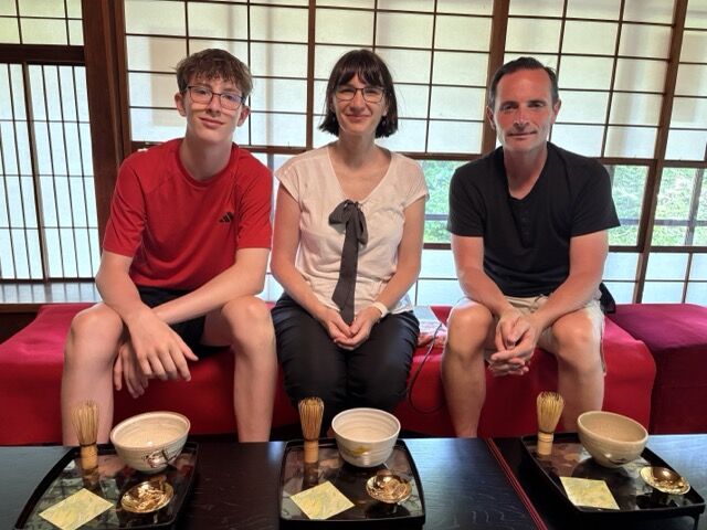 Christel Billault seated between two family members during a tea experience in Japan