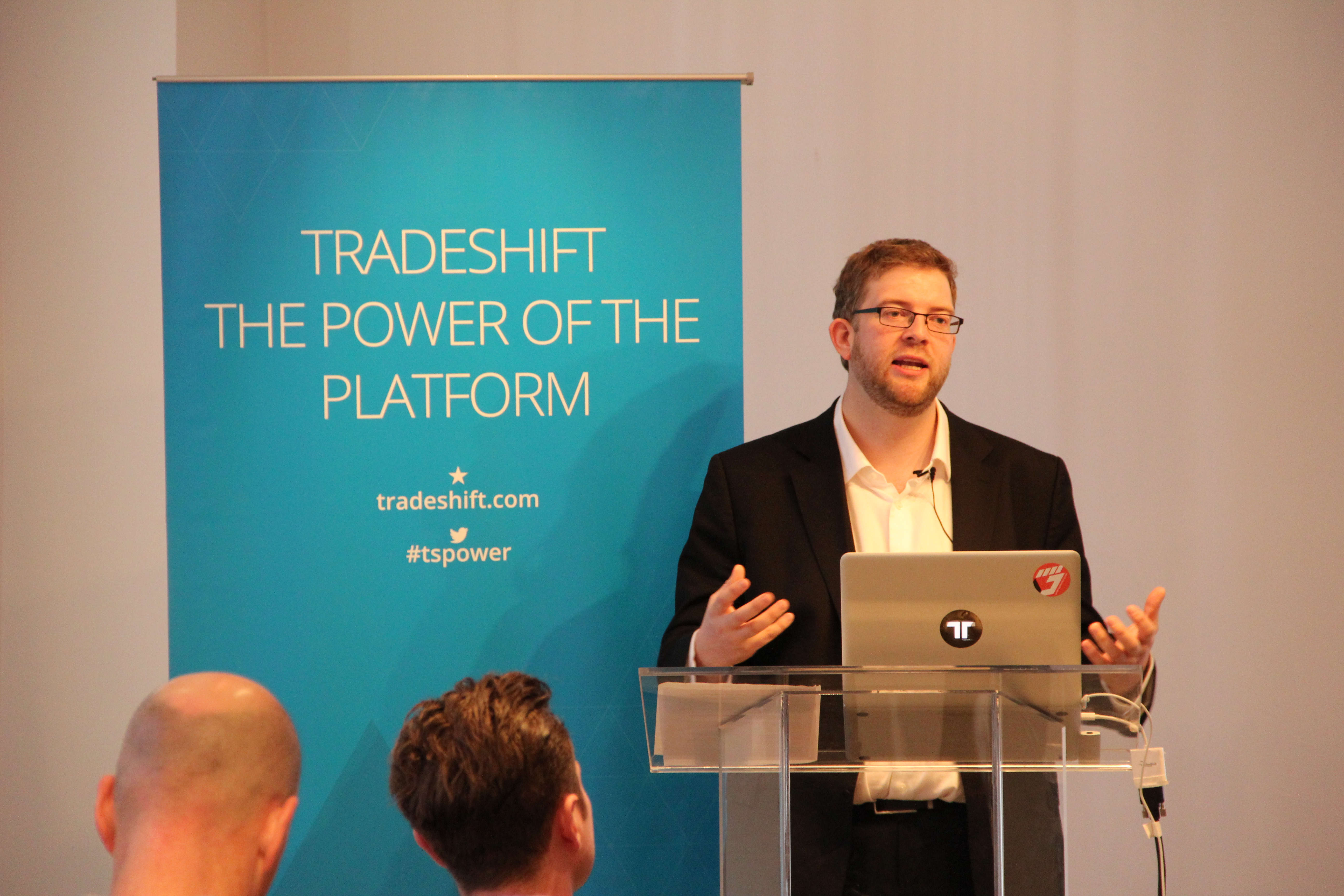 Christian Lanng speaking behind a lectern beside a Tradeshift banner