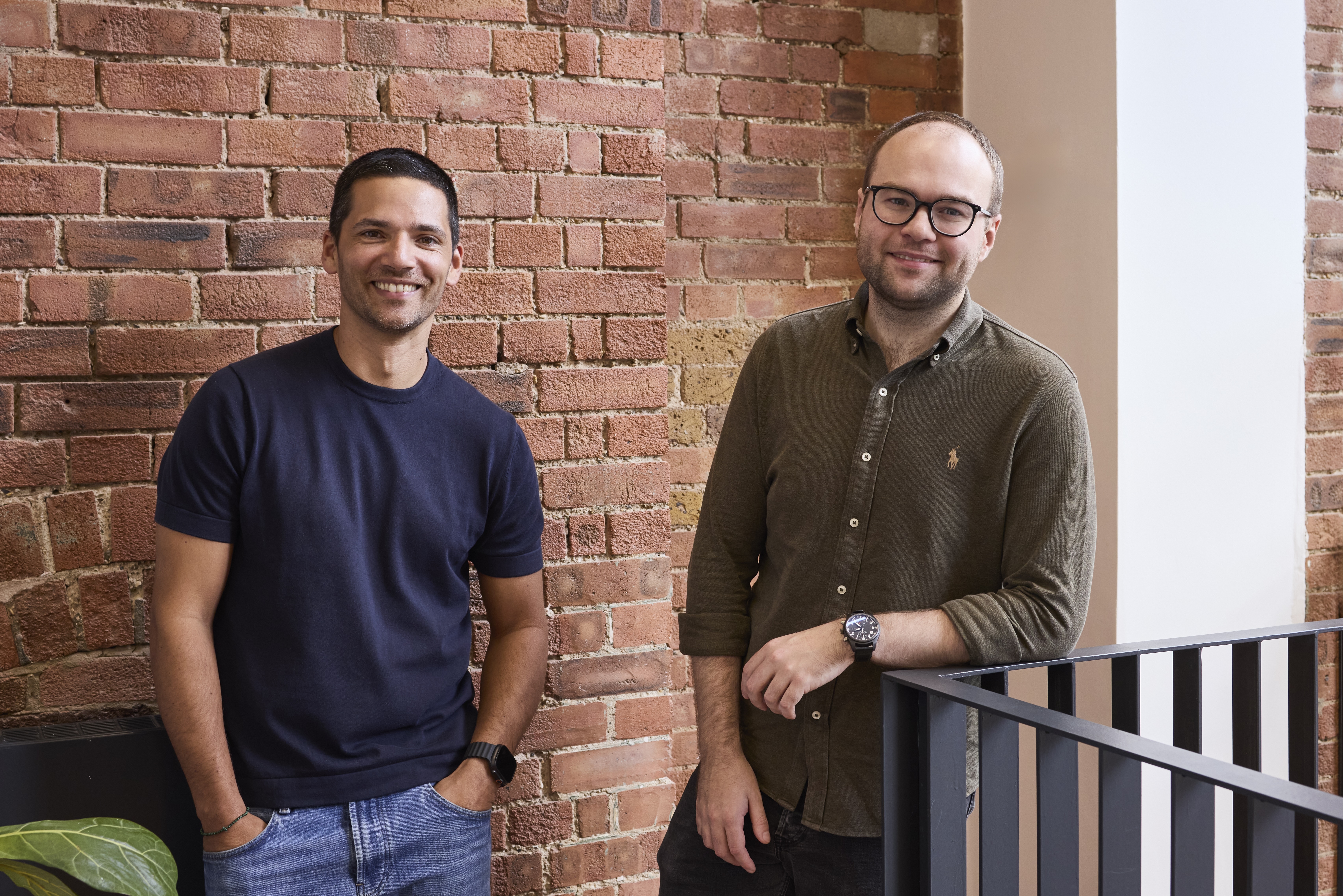 Alex Loizou and Christian Owens standing beside a brick wall in Clove’s office