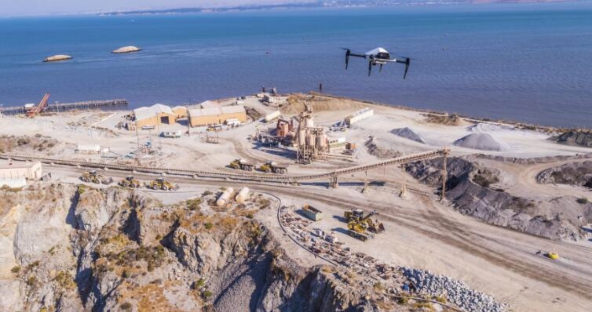 A Skycatch drone flying above a large industrial quarry near the water