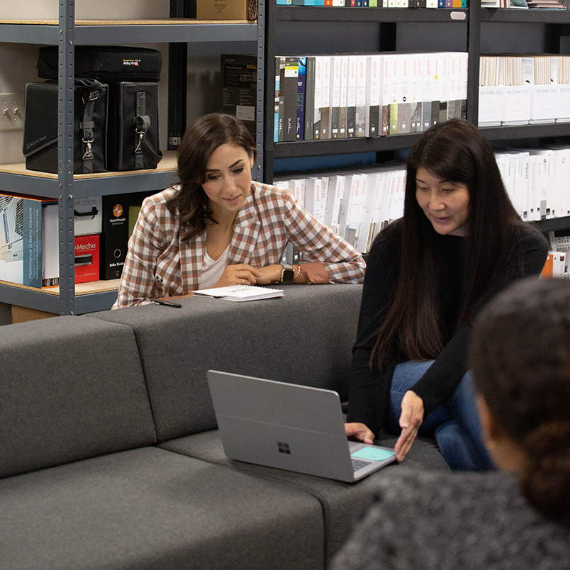 Christie Porter and colleagues discussing work around a laptop in a studio materials library