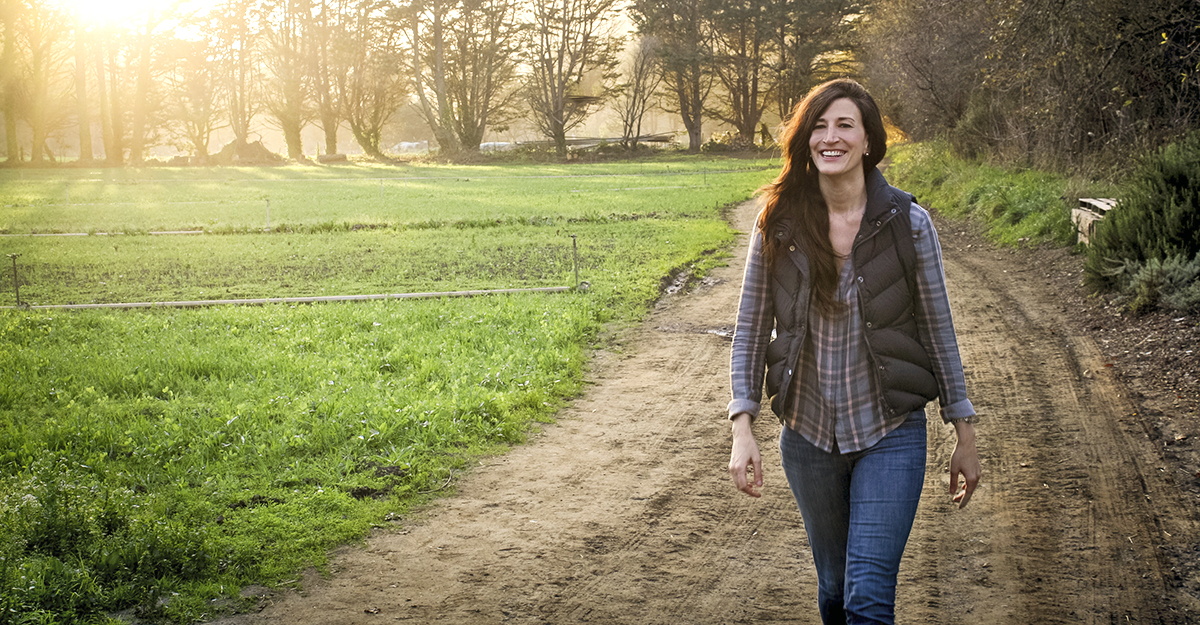 Christine Moseley walking along a farm track beside green fields