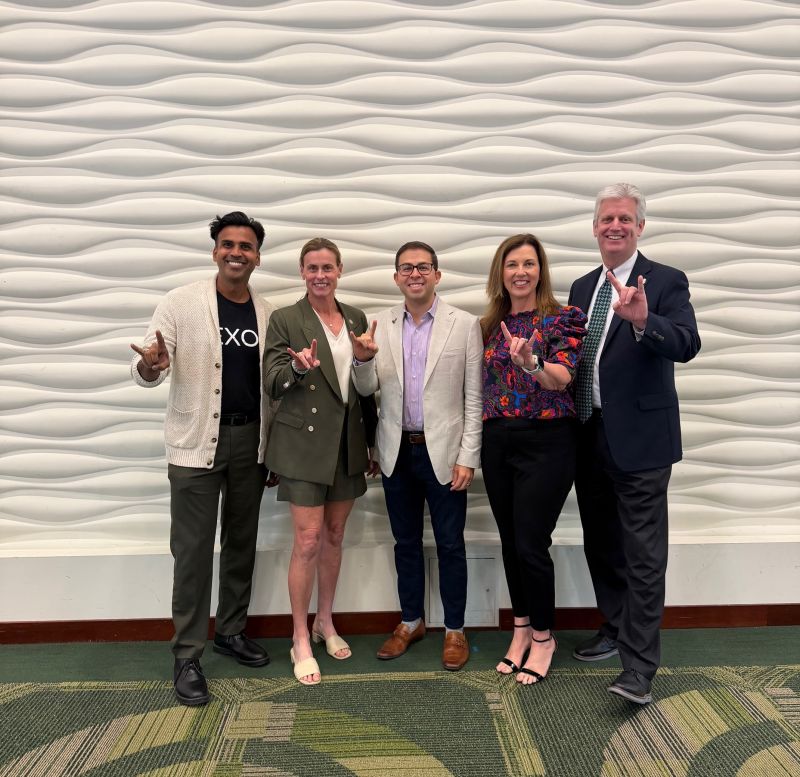 Christine Turner with four USF Alumni Association colleagues, all making the Bulls hand gesture