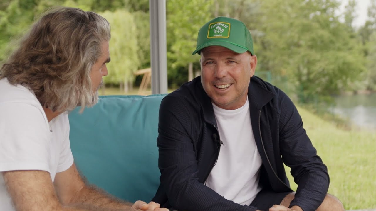 Christoph Sonnen, wearing a green cap, in conversation with Nils Glagau beside a lake