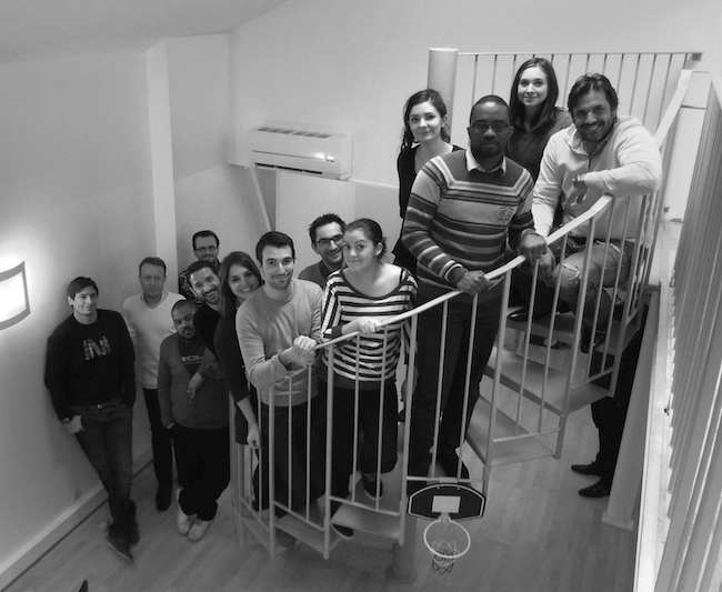 Early S4M team gathered on an office staircase beside a small basketball hoop