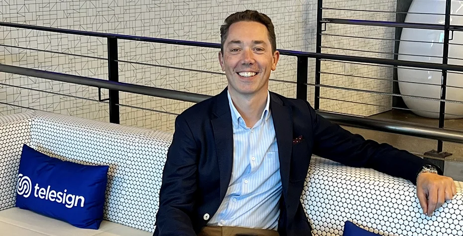 Christophe Van de Weyer seated on an office sofa beside a Telesign cushion