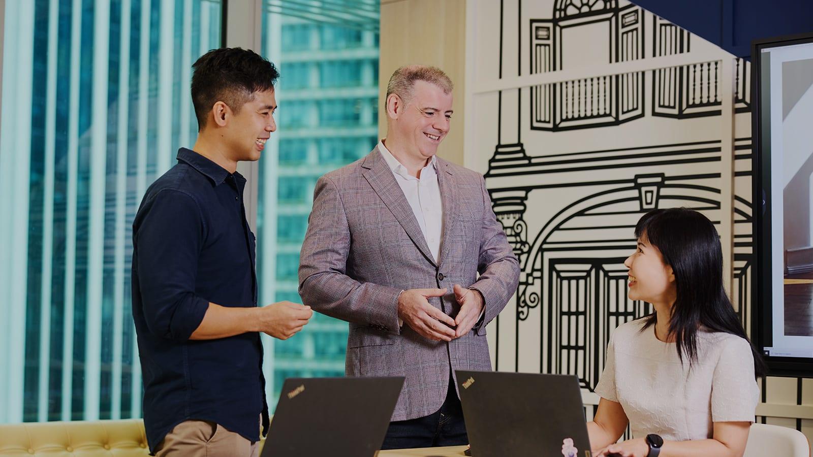 Christopher Albrecht, centre, talking with two colleagues beside open laptops