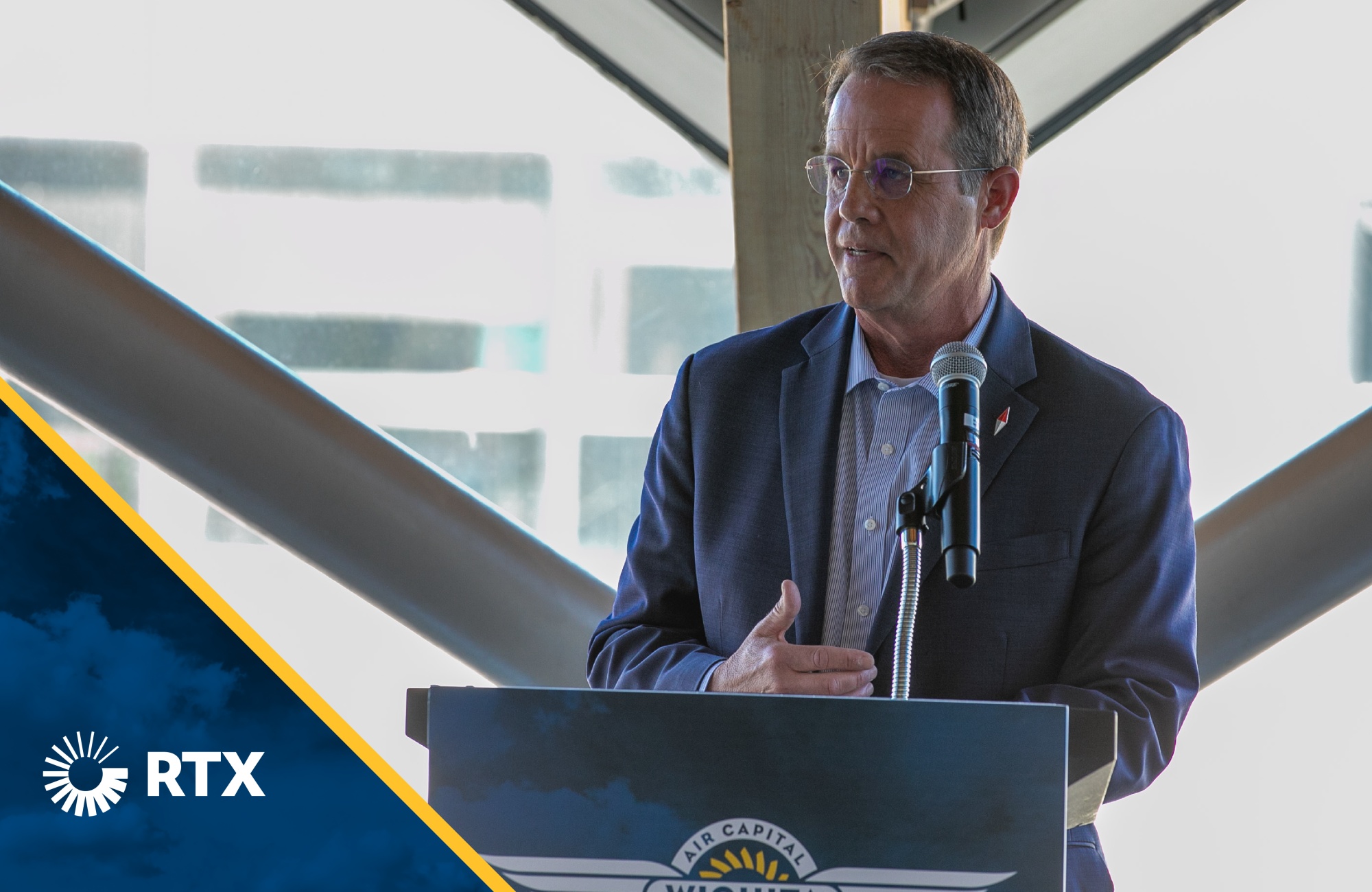 Christopher Calio speaking into a microphone at an aerospace gathering in Wichita